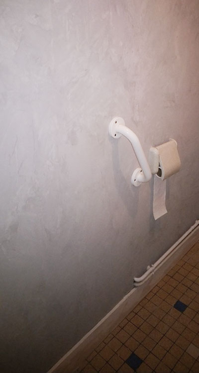 Mur de toilettes recouvert d'un enduit effet béton gris