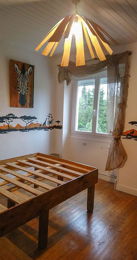 Photo du résultat de la chambre jungle : vue sur un bout du lit, la suspension, la frise et un tableau zèbre