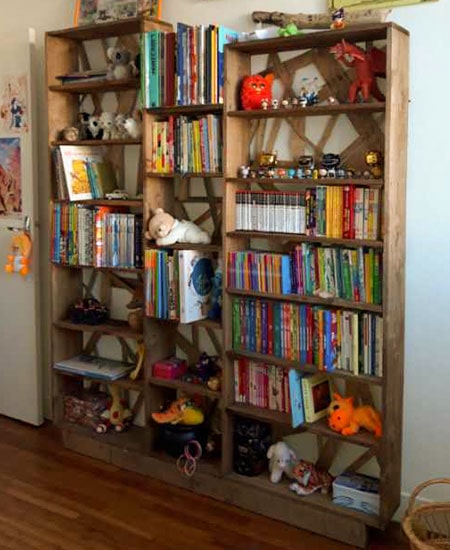 Bibliothèque en bois massif avec fond cagettes remplie de livres et jouets