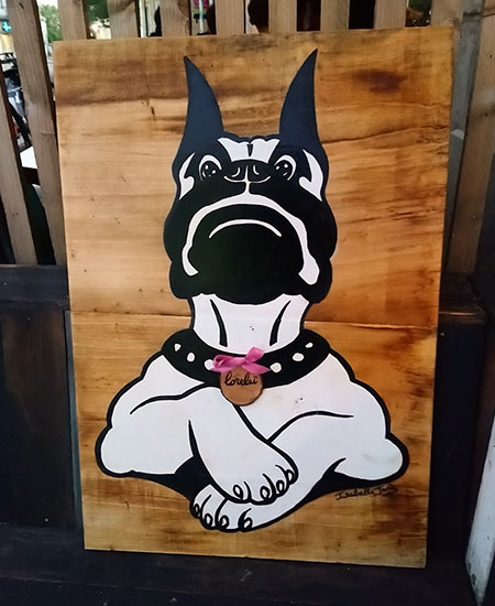 Peinture d'un chien cartoonisé sur planches de bois avec ajout d'une médaille en rondelle de bois