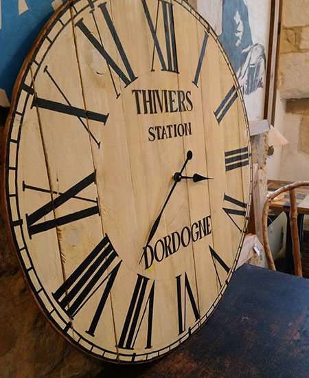Horloge de style industriel avec indiqué 'Thiviers Station Dordogne' vue sur le côté