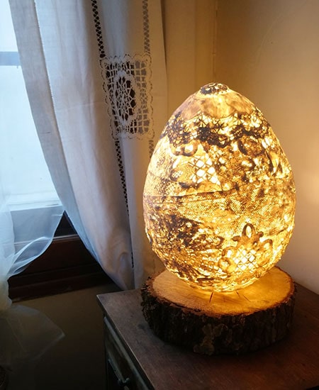 Lampe avec abat-jour œuf en dentelles allumée
