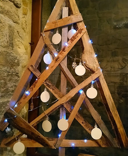 Sapin en bois de récupération décoré avec boules en tranches de bûchettes et petite guirlande