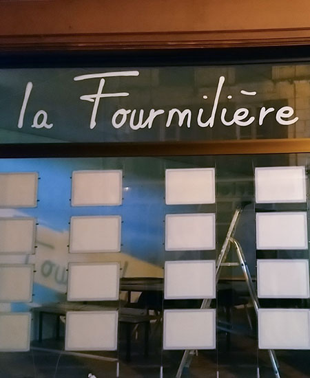 Peinture logotype 'la fourmilière' sur une vitrine verre : gros plan